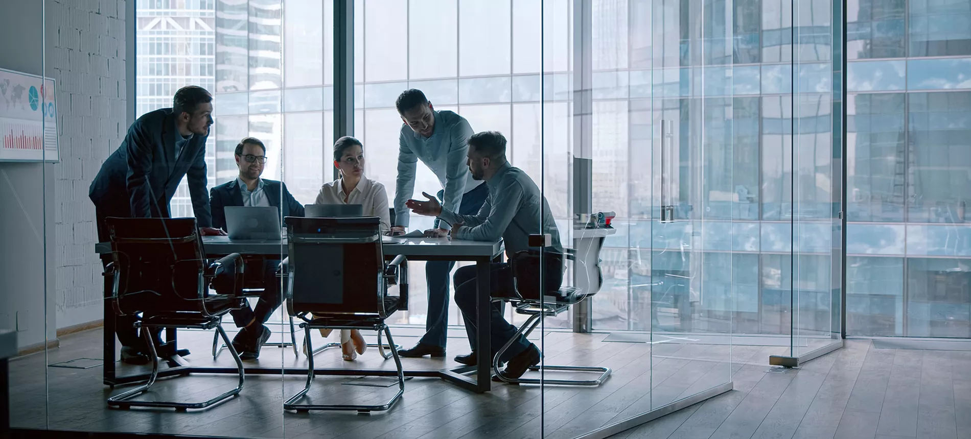 five persons in a meeting in a glass office