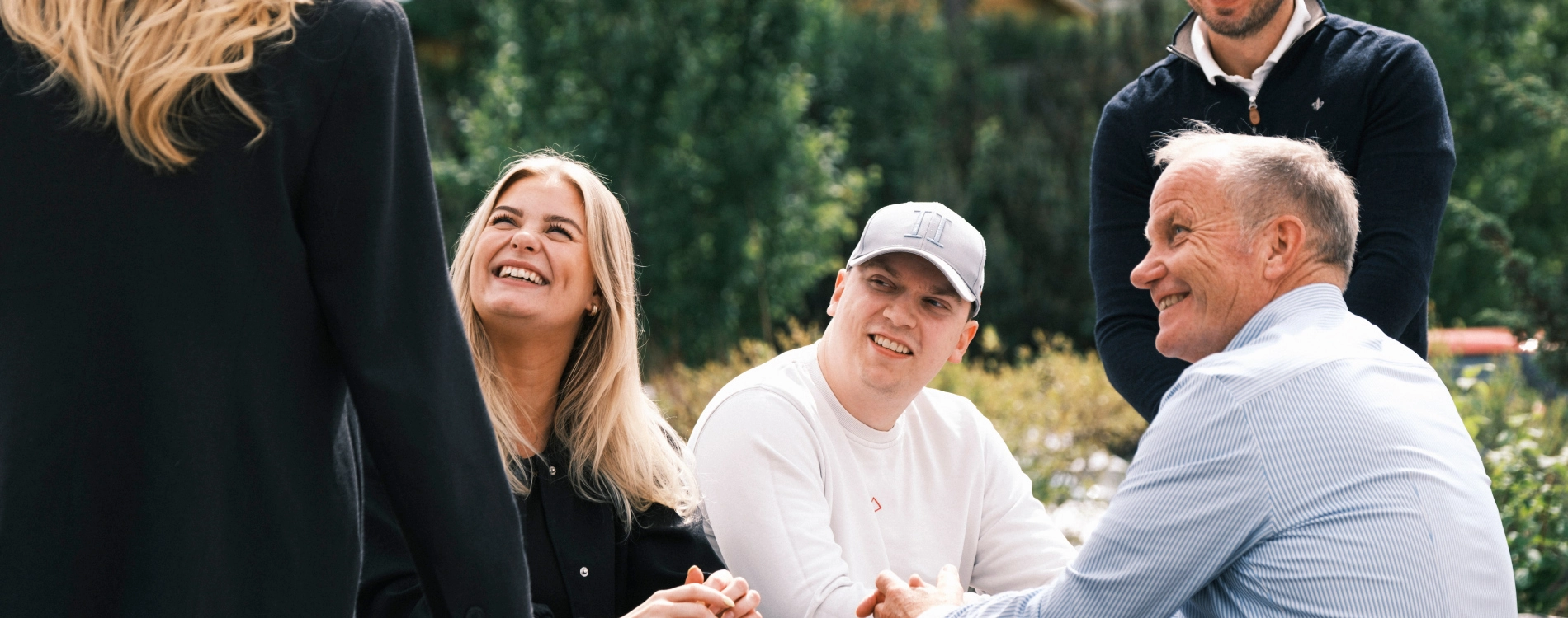 Five People Sitting Outside Smiling And Talking