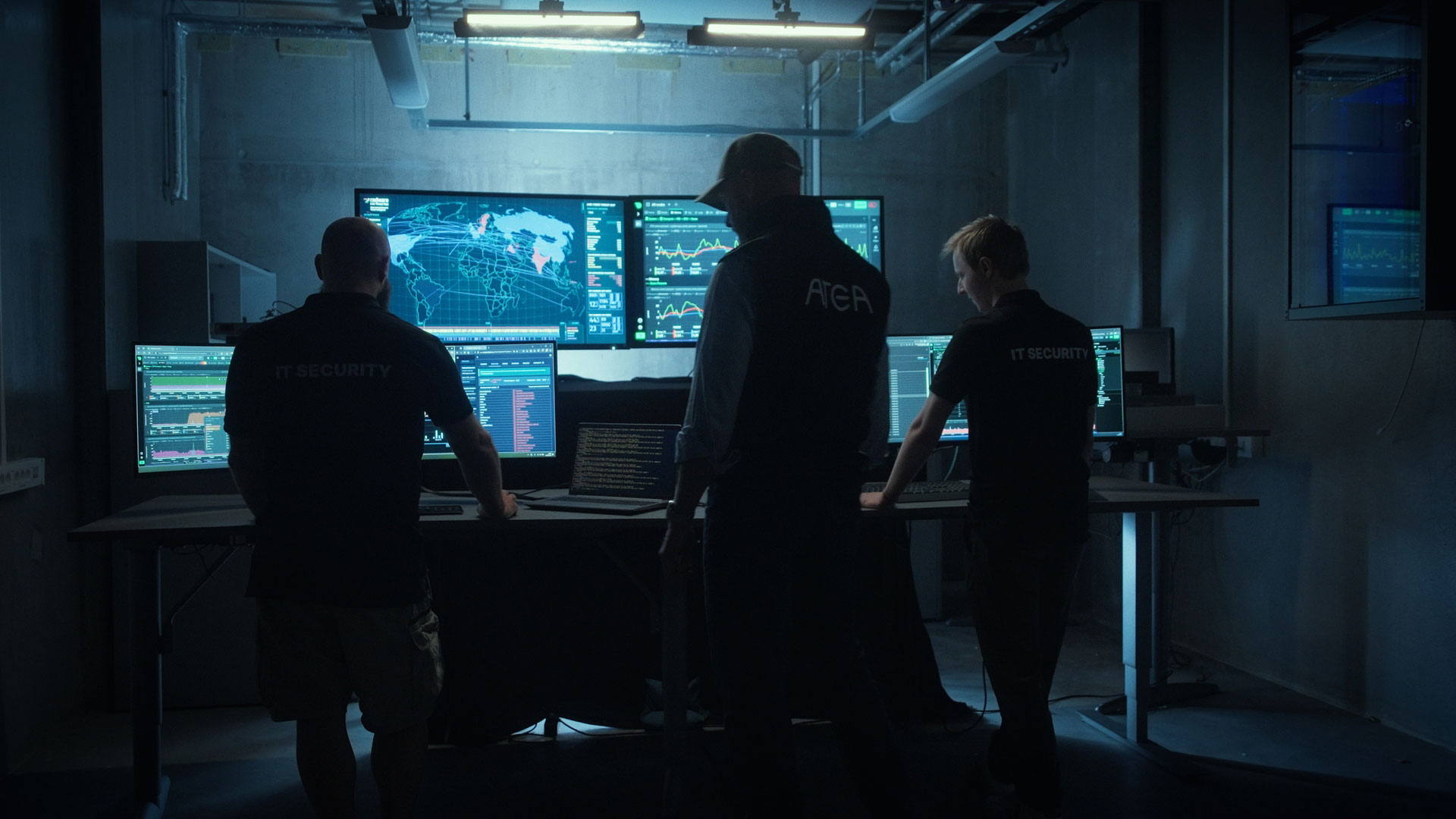 Three-people-standing-in-front-of-screens-with-security-data